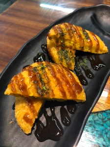 four pieces of pumpkin croquette with sweet sauce drizzled over